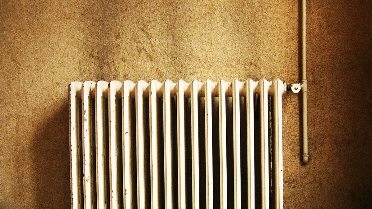 Radiateur en fonte à eau chaude sous une fenêtre dans un immeuble parisien